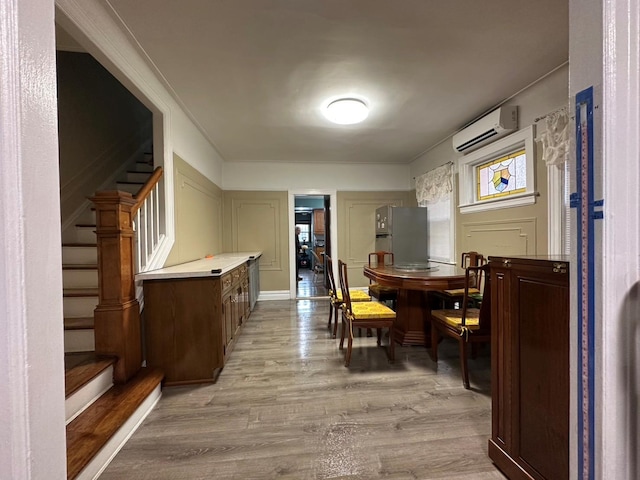 dining room with light hardwood / wood-style flooring and a wall unit AC