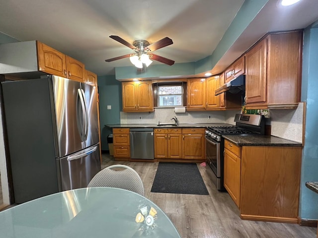 kitchen featuring appliances with stainless steel finishes, backsplash, ceiling fan, sink, and hardwood / wood-style floors