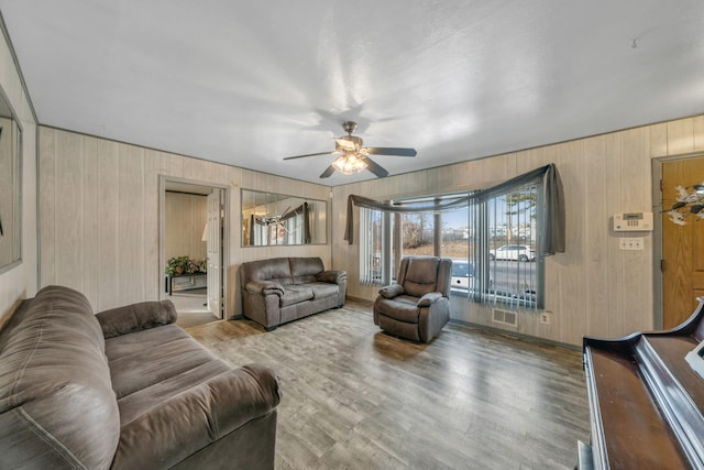 living room with ceiling fan, wooden walls, and hardwood / wood-style flooring