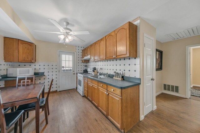 kitchen featuring decorative backsplash, white appliances, light hardwood / wood-style floors, and ceiling fan