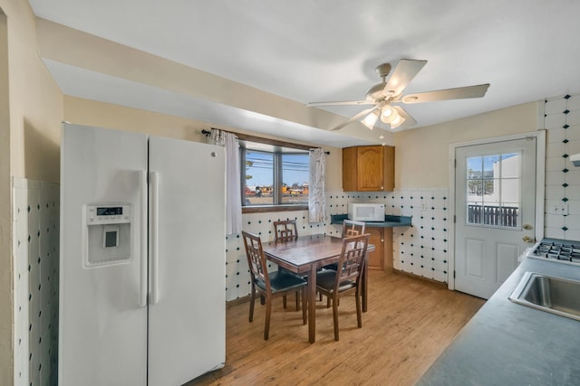 kitchen with plenty of natural light, ceiling fan, white appliances, and light hardwood / wood-style flooring