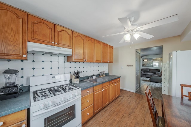 kitchen featuring light wood-type flooring, tasteful backsplash, white appliances, ceiling fan, and sink