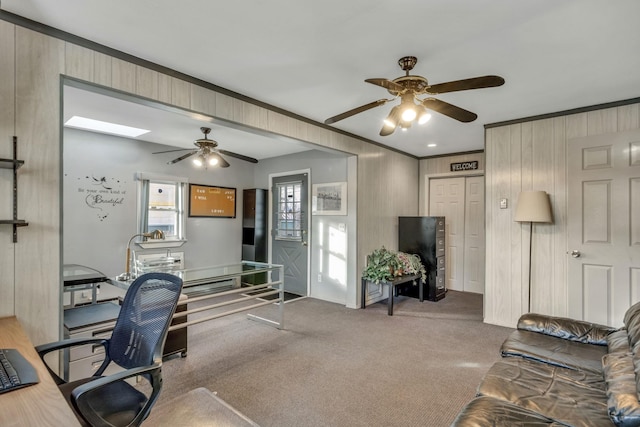 carpeted office space featuring ceiling fan and wooden walls