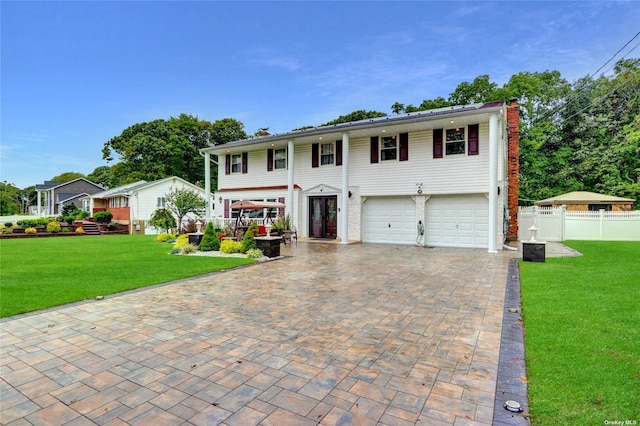 view of front of home featuring a garage, a chimney, fence, decorative driveway, and a front lawn