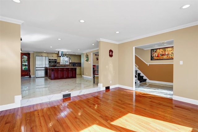 unfurnished living room featuring stairway, visible vents, light wood finished floors, and crown molding