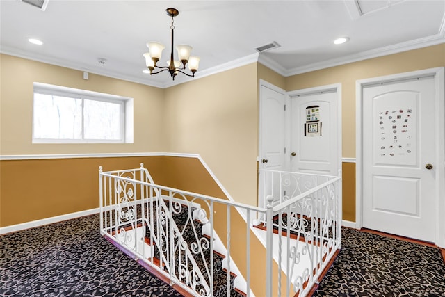 corridor featuring baseboards, an upstairs landing, crown molding, carpet flooring, and a chandelier