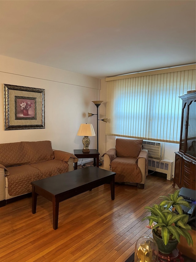 living room with wood-type flooring, radiator heating unit, and a wall unit AC