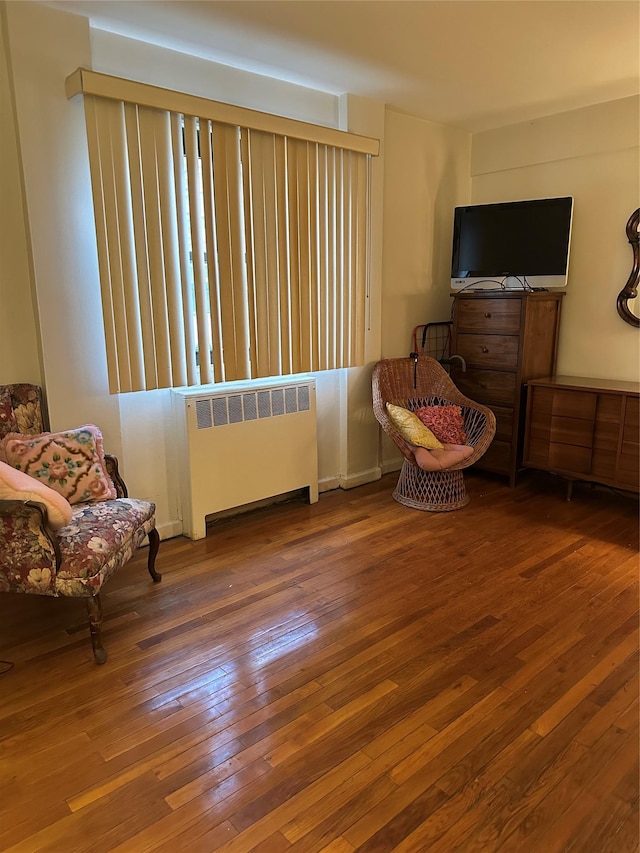 sitting room with radiator heating unit and hardwood / wood-style flooring