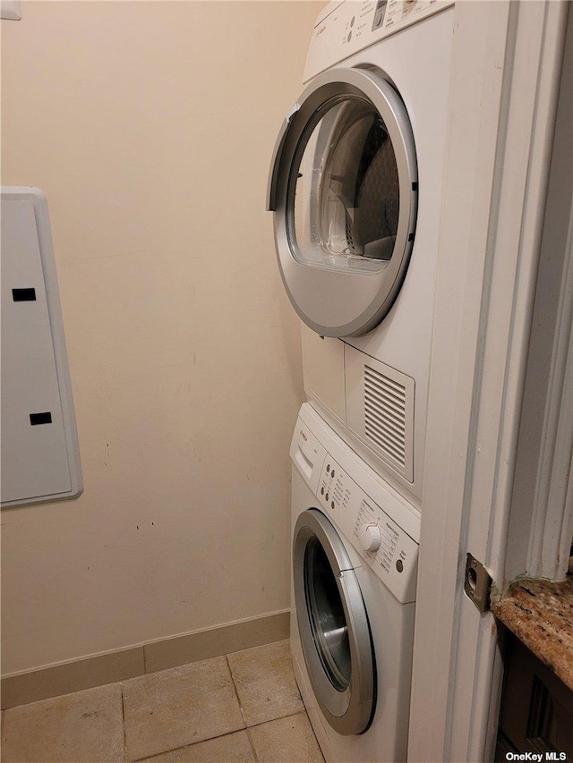 clothes washing area with electric panel, light tile patterned floors, and stacked washer / drying machine