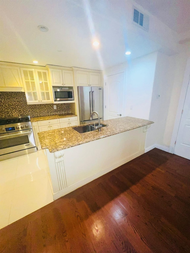 kitchen featuring backsplash, dark wood-type flooring, sink, light stone countertops, and appliances with stainless steel finishes