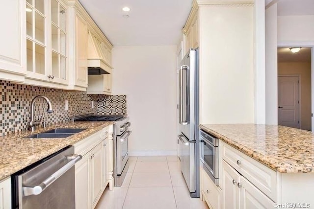 kitchen featuring sink, light stone counters, cream cabinets, light tile patterned floors, and high end appliances