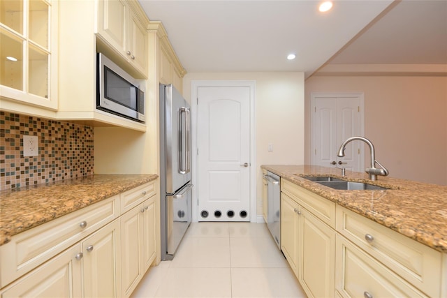 kitchen featuring light stone countertops, sink, stainless steel appliances, tasteful backsplash, and light tile patterned floors