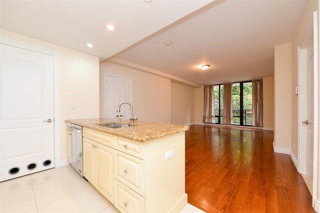 kitchen with dishwasher, light stone countertops, sink, and cream cabinets