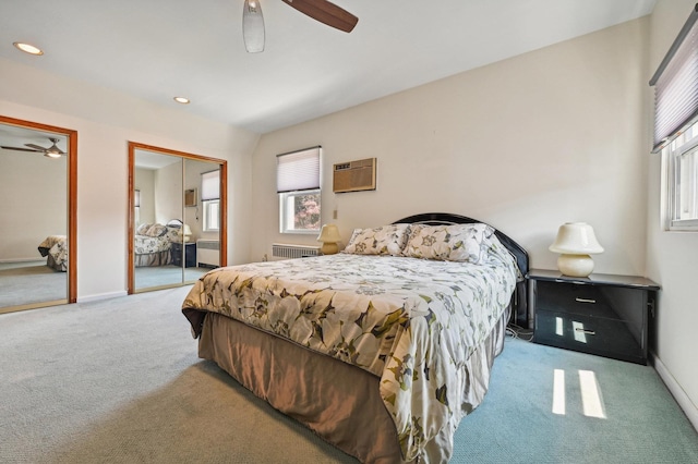 carpeted bedroom with radiator heating unit, multiple closets, a wall mounted AC, and ceiling fan