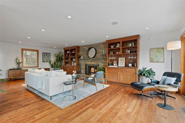 living room with a stone fireplace and light hardwood / wood-style floors