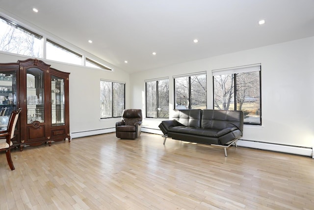 living room featuring light hardwood / wood-style floors, baseboard heating, and high vaulted ceiling