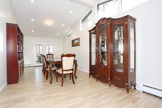 dining space with a baseboard heating unit, vaulted ceiling, and light hardwood / wood-style flooring