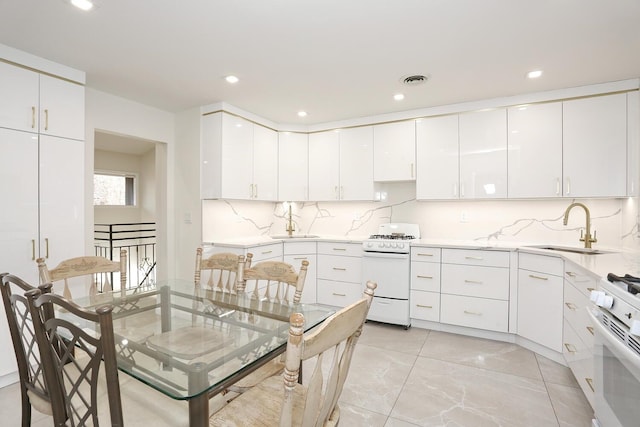 kitchen featuring sink, white cabinets, and white range with gas cooktop