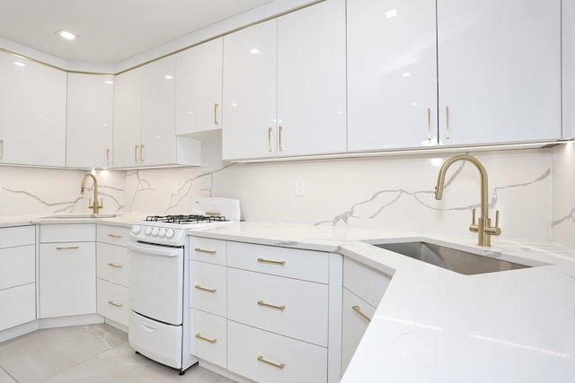 kitchen featuring sink, white cabinets, tasteful backsplash, and white gas range