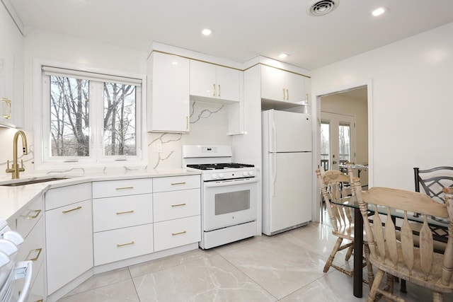 kitchen with white appliances, light stone counters, sink, white cabinetry, and tasteful backsplash