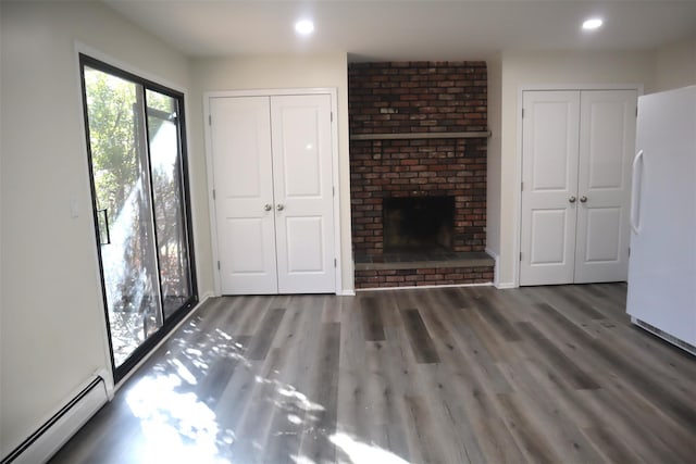 unfurnished living room featuring a baseboard heating unit, a brick fireplace, and dark hardwood / wood-style floors