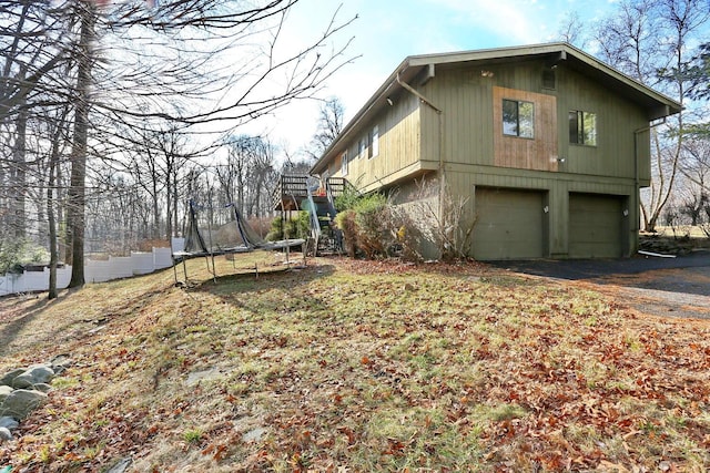 view of side of property with a garage and a trampoline