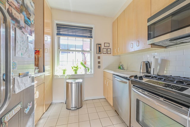 kitchen featuring light tile patterned floors, stainless steel appliances, light brown cabinets, backsplash, and sink