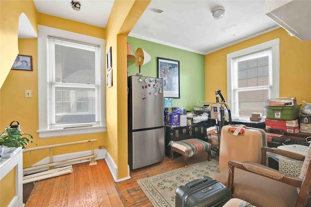 kitchen with stainless steel fridge, wood-type flooring, crown molding, and a wealth of natural light