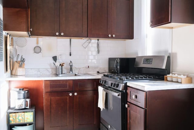 kitchen featuring tasteful backsplash, sink, and stainless steel range with gas stovetop