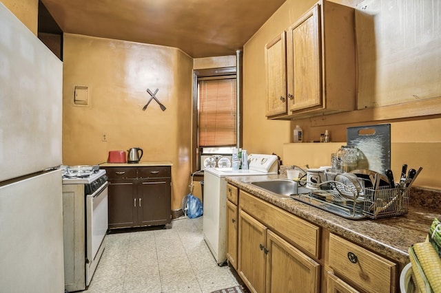 kitchen featuring a sink, white appliances, light floors, and washing machine and dryer