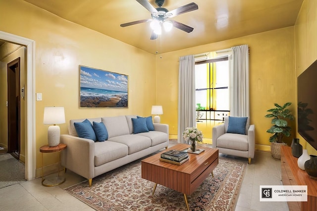 living area with baseboards and a ceiling fan