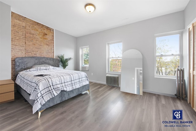 bedroom featuring radiator heating unit and hardwood / wood-style flooring