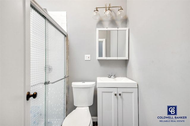 bathroom featuring vanity, toilet, and a shower with shower door