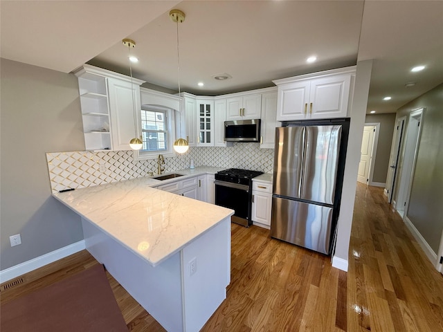 kitchen with pendant lighting, white cabinets, decorative backsplash, appliances with stainless steel finishes, and kitchen peninsula