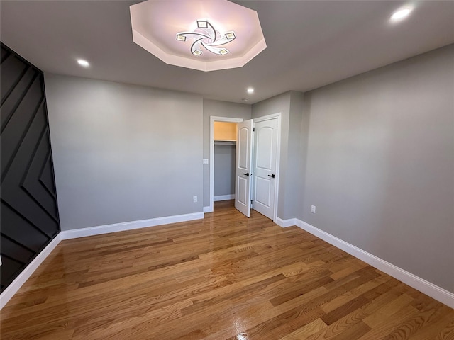 unfurnished room with light wood-type flooring and a tray ceiling