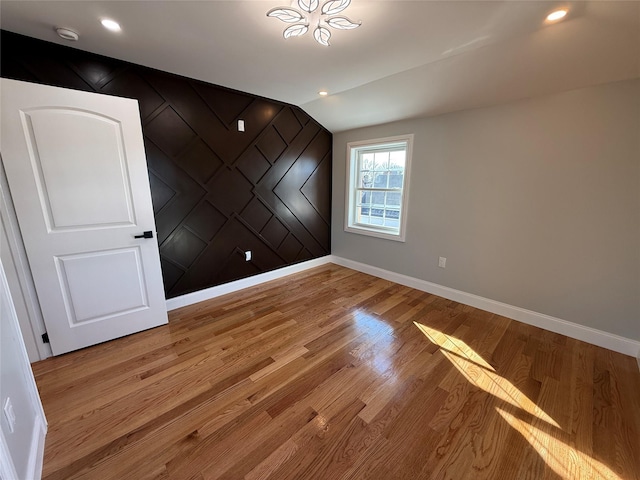 unfurnished room with hardwood / wood-style floors and lofted ceiling