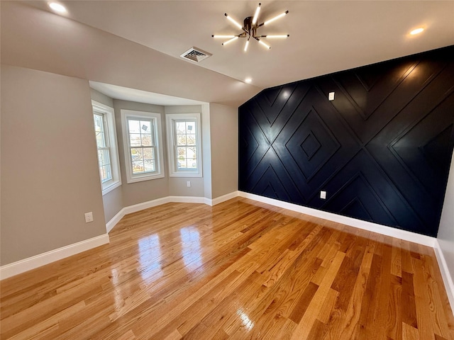 empty room featuring light hardwood / wood-style flooring and a notable chandelier