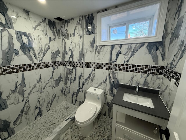 bathroom with a shower, vanity, toilet, and tile walls