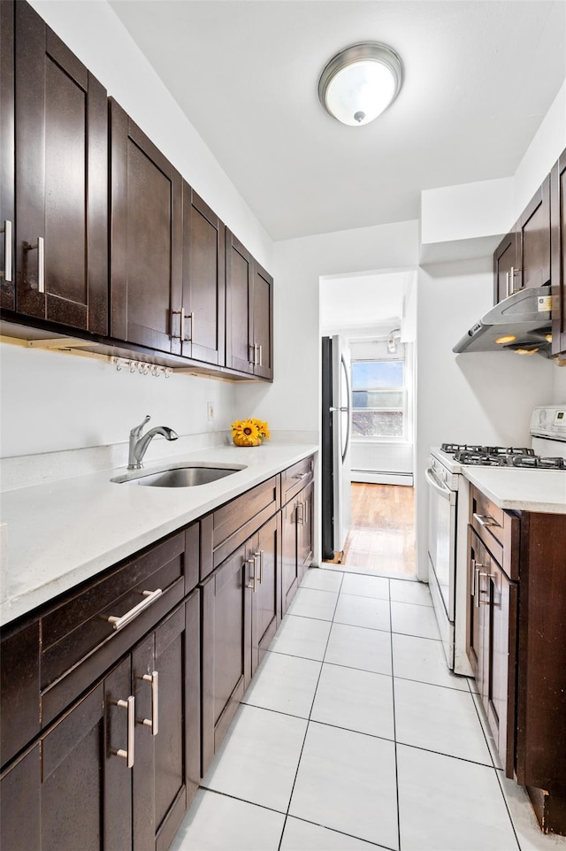 kitchen featuring sink, white gas range, stainless steel fridge, and dark brown cabinetry