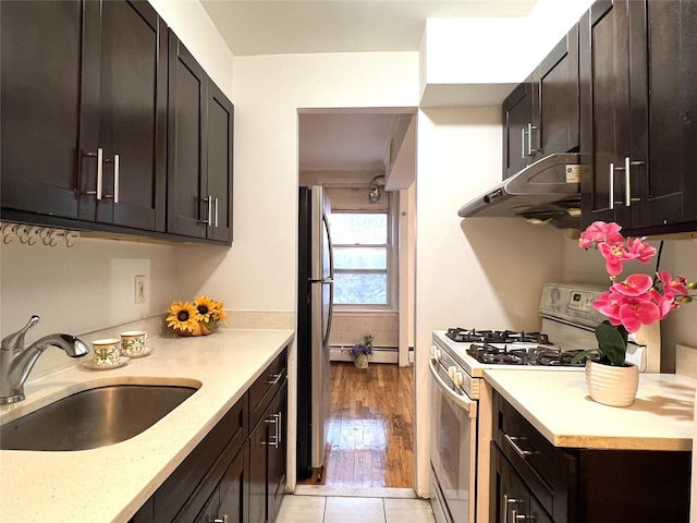 kitchen with sink, light tile patterned floors, white range with gas stovetop, stainless steel refrigerator, and dark brown cabinetry