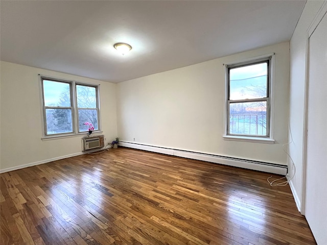 spare room featuring dark wood-type flooring, a wealth of natural light, and a baseboard heating unit