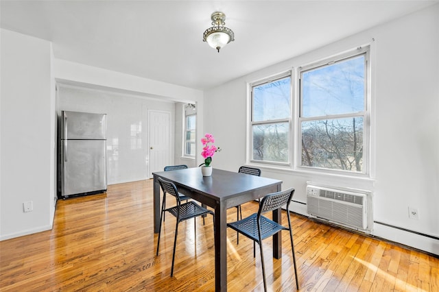 dining space with light wood-type flooring and a wall mounted air conditioner