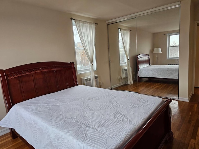 bedroom with hardwood / wood-style floors, a wall unit AC, and a closet