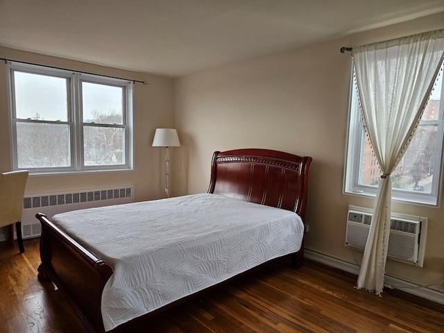 bedroom featuring dark hardwood / wood-style floors, a wall unit AC, and radiator