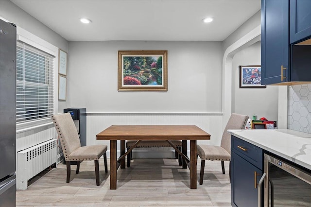 dining room featuring radiator heating unit, beverage cooler, and light hardwood / wood-style flooring