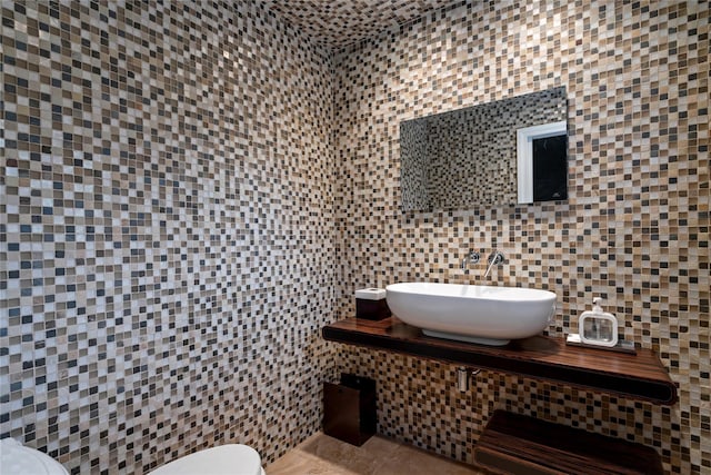 bathroom with tile patterned floors, toilet, tile walls, and sink