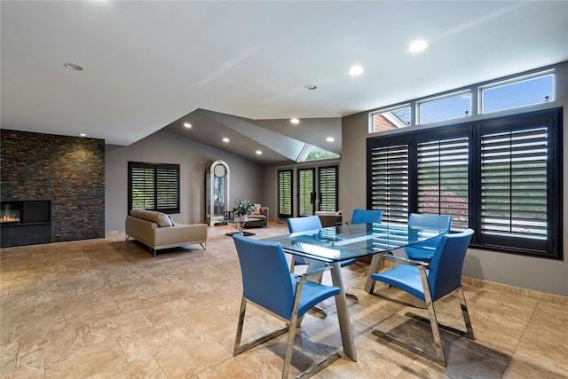 dining room with a fireplace and vaulted ceiling