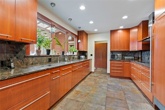 kitchen with sink, tasteful backsplash, dark stone countertops, pendant lighting, and black electric stovetop