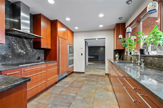 kitchen featuring sink, wall chimney range hood, tasteful backsplash, pendant lighting, and black appliances