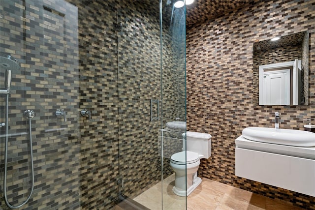 bathroom featuring tile patterned floors, an enclosed shower, sink, tile walls, and toilet